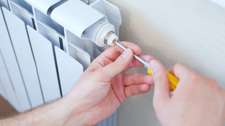Technicien en plomberie intervenant sur installation de chauffage domestique dans local technique résidentiel